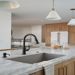Light brown and gray kitchen remodel with hanging lights and granite counters